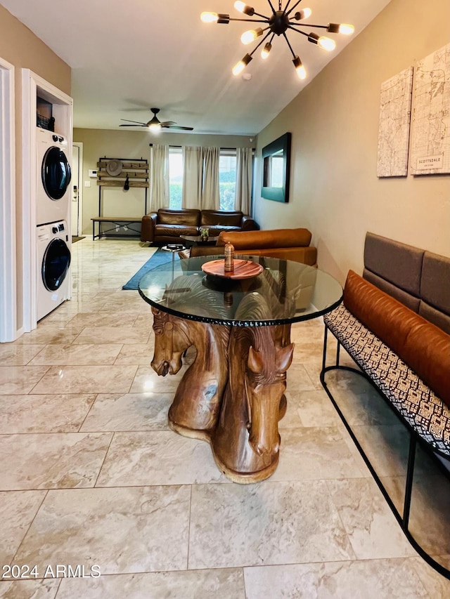 dining space featuring ceiling fan with notable chandelier and stacked washer / drying machine