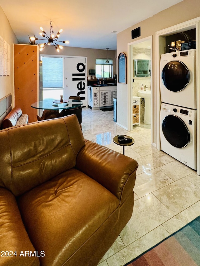 living area with a chandelier and stacked washing maching and dryer