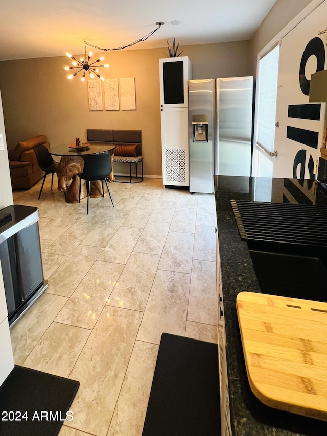 kitchen with stainless steel fridge with ice dispenser and a chandelier