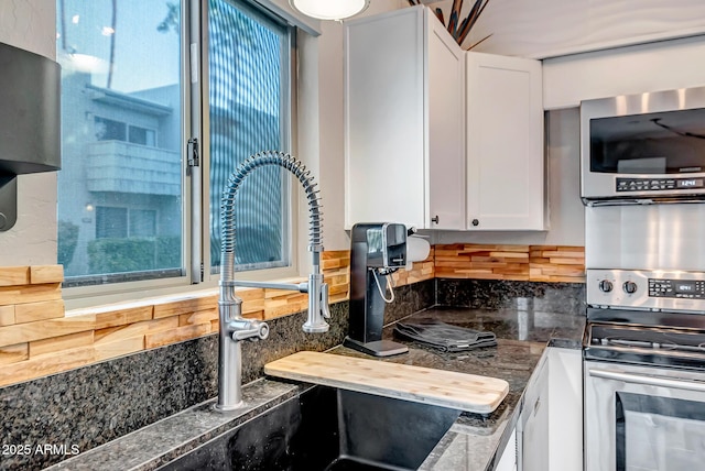 kitchen with tasteful backsplash, white cabinetry, and electric range