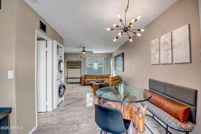 dining area featuring ceiling fan with notable chandelier, stacked washer and dryer, visible vents, and baseboards