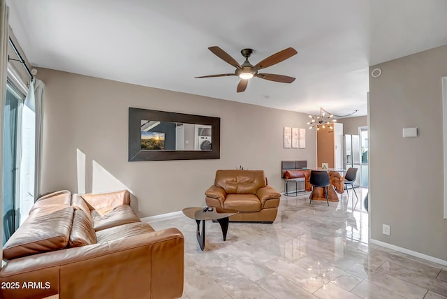 living area featuring marble finish floor, baseboards, and ceiling fan with notable chandelier