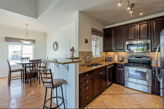 5335 E Shea Blvd Unit 2081, Scottsdale, AZ 85254 - kitchen with appliances with stainless steel finishes, decorative backsplash, dark brown cabinets, stone countertops, and a kitchen breakfast bar