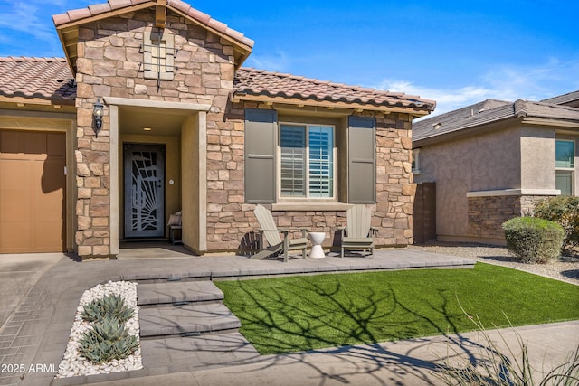 view of exterior entry with stone siding, stucco siding, and a tiled roof