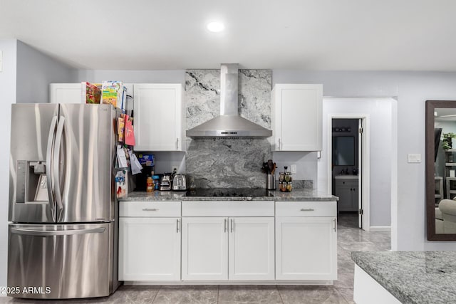 kitchen featuring white cabinets, light stone counters, black electric stovetop, wall chimney range hood, and stainless steel refrigerator with ice dispenser