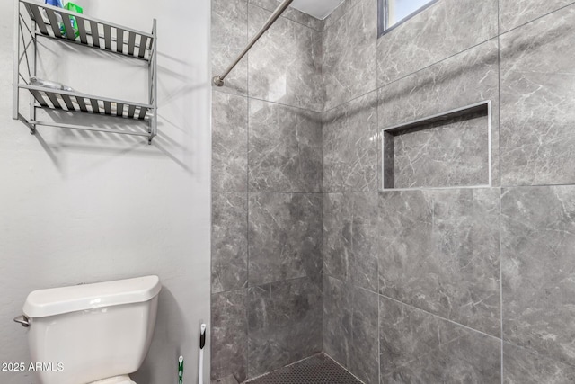 bathroom featuring tiled shower and toilet