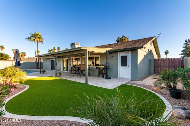 back of property featuring a fenced in pool, a lawn, a patio, and ceiling fan