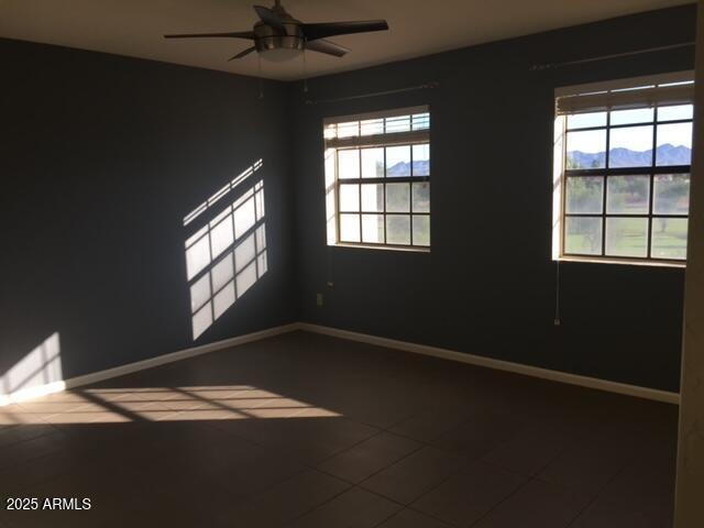 empty room with tile patterned flooring, a mountain view, and ceiling fan