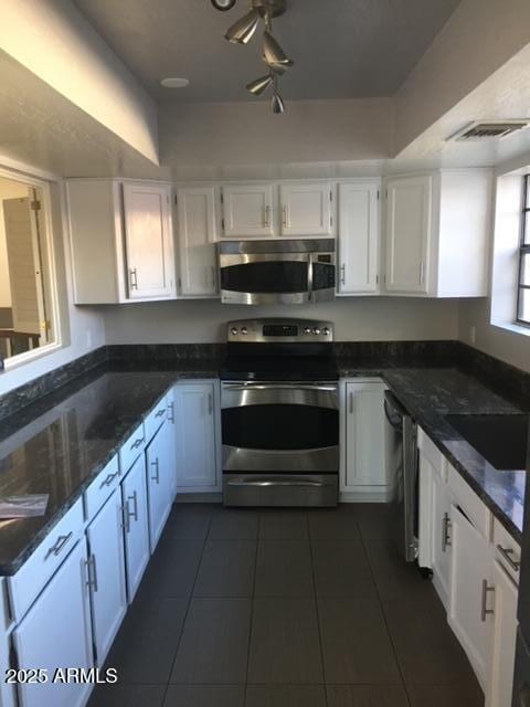 kitchen featuring white cabinets, dark tile patterned flooring, and appliances with stainless steel finishes