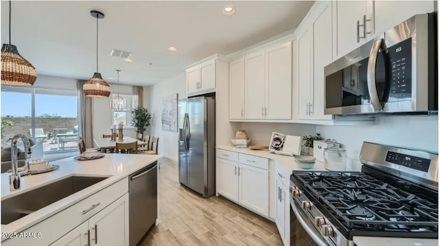 1516 W Ridge Rd, Apache Junction, AZ 85120 - kitchen featuring stainless steel appliances, a sink, white cabinets, light wood-style flooring, and light countertops