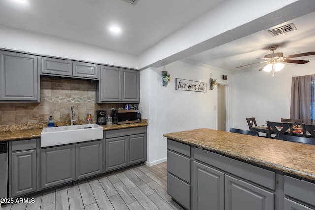 kitchen with sink, gray cabinetry, ceiling fan, stainless steel appliances, and decorative backsplash