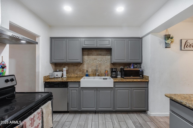 kitchen featuring sink, gray cabinets, stainless steel appliances, decorative backsplash, and wall chimney exhaust hood