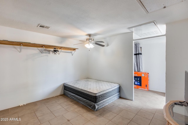 bedroom with ceiling fan, light tile patterned flooring, and a textured ceiling