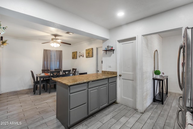 kitchen featuring crown molding, gray cabinets, stainless steel refrigerator, ceiling fan, and kitchen peninsula