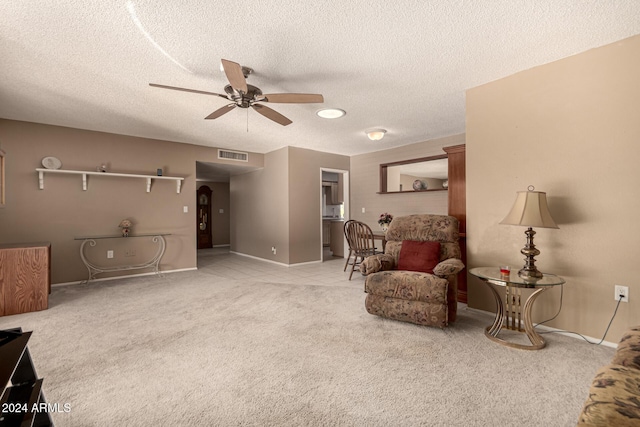 living area featuring a textured ceiling, carpet floors, and ceiling fan