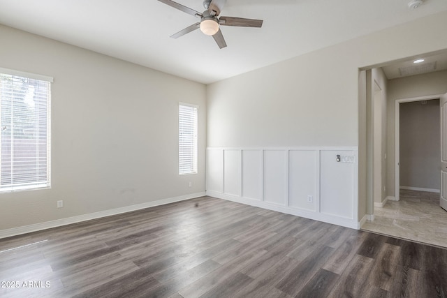 empty room with ceiling fan, wood finished floors, and baseboards