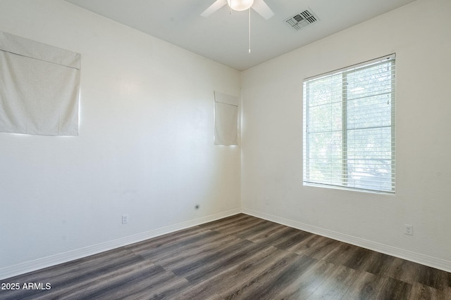 empty room with dark wood-style floors, a ceiling fan, and baseboards