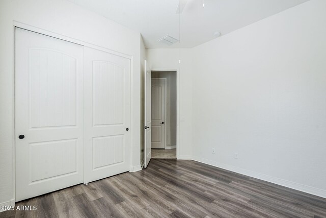 unfurnished bedroom featuring wood finished floors, a closet, and baseboards