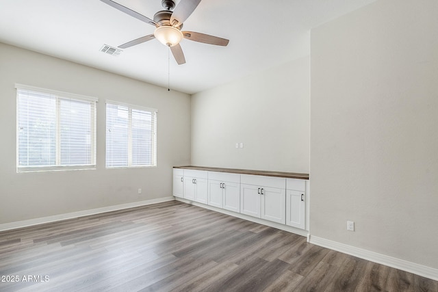 spare room featuring wood finished floors, ceiling fan, and baseboards