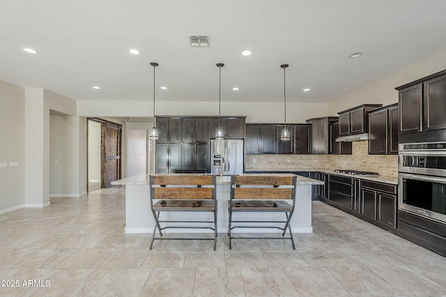 kitchen with appliances with stainless steel finishes, recessed lighting, a kitchen island, decorative backsplash, and light stone countertops