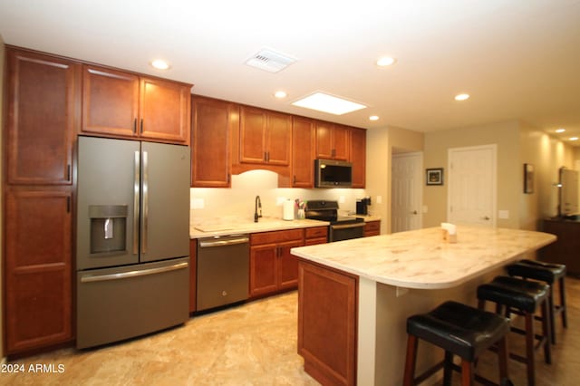 kitchen featuring appliances with stainless steel finishes, a center island, and a breakfast bar area