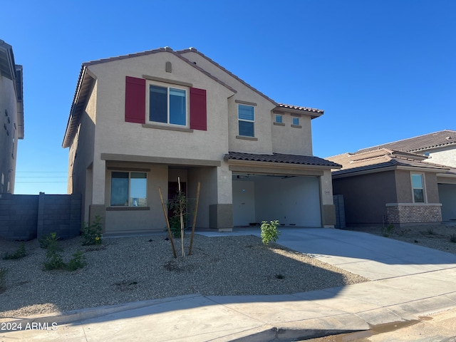 view of front facade with an attached garage, fence, a tile roof, concrete driveway, and stucco siding