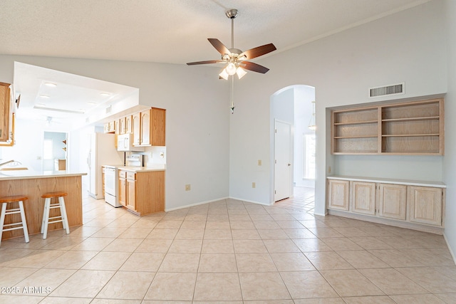 unfurnished living room featuring sink, ceiling fan, a textured ceiling, light tile patterned flooring, and vaulted ceiling