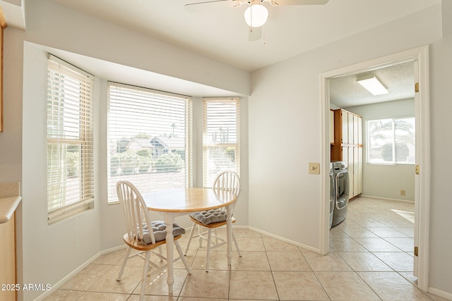 unfurnished dining area with light tile patterned floors, a textured ceiling, washer and dryer, and ceiling fan