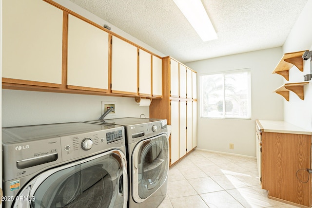 clothes washing area featuring cabinets, light tile patterned floors, a textured ceiling, and washer and clothes dryer