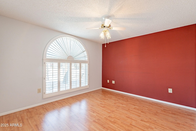 unfurnished room with ceiling fan, a textured ceiling, and light wood-type flooring