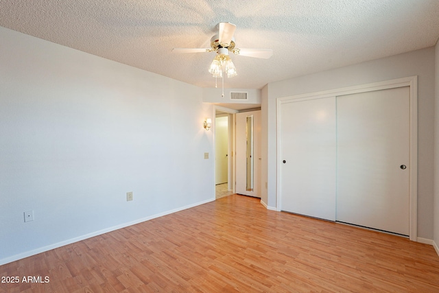 unfurnished bedroom with ceiling fan, a textured ceiling, light wood-type flooring, and a closet