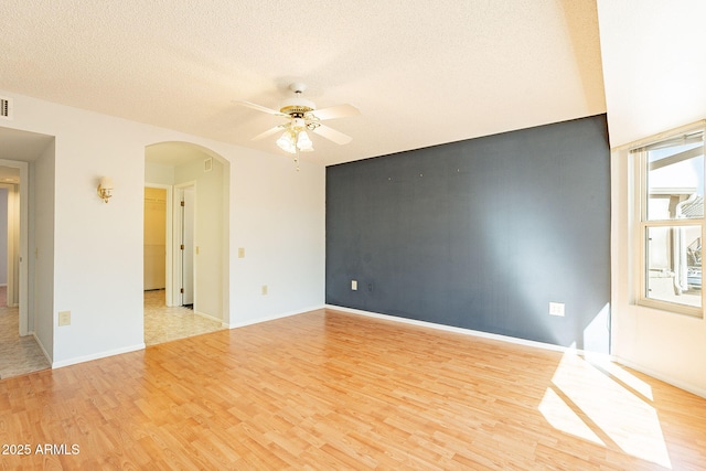 spare room featuring ceiling fan, light hardwood / wood-style flooring, and a textured ceiling