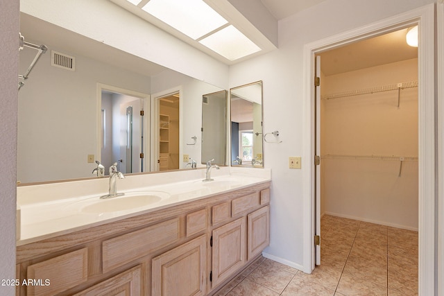 bathroom with tile patterned floors, vanity, and a skylight