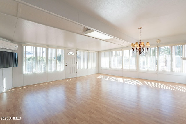 unfurnished sunroom with plenty of natural light, a chandelier, and a wall unit AC