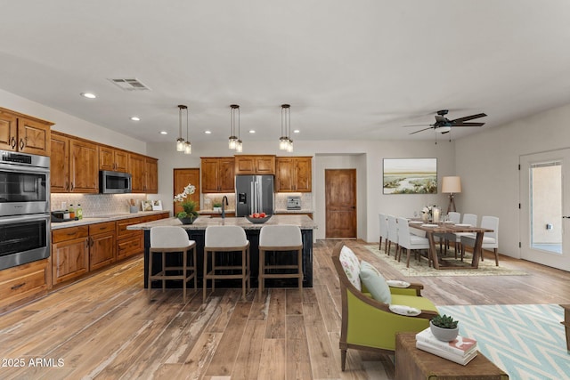 kitchen featuring pendant lighting, appliances with stainless steel finishes, a center island, tasteful backsplash, and a kitchen bar