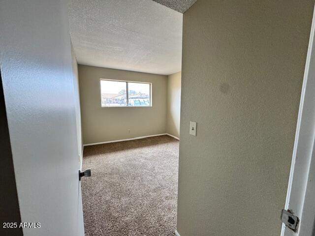 carpeted empty room with a textured ceiling