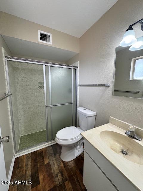 bathroom featuring an enclosed shower, wood-type flooring, vanity, and toilet