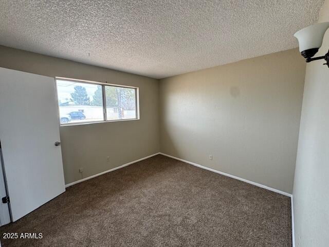 unfurnished room with dark carpet and a textured ceiling