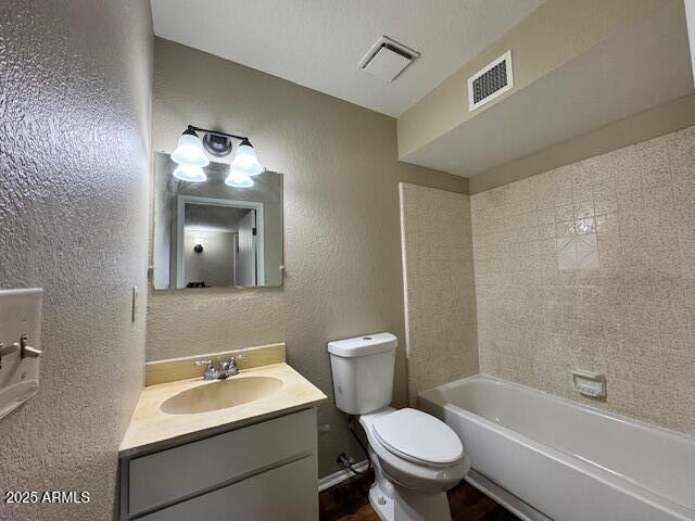 full bathroom with vanity, toilet, tiled shower / bath combo, and a textured ceiling