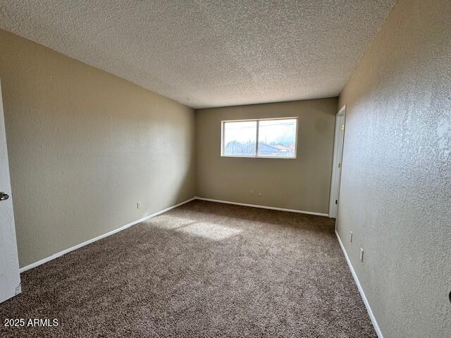 carpeted empty room featuring a textured ceiling