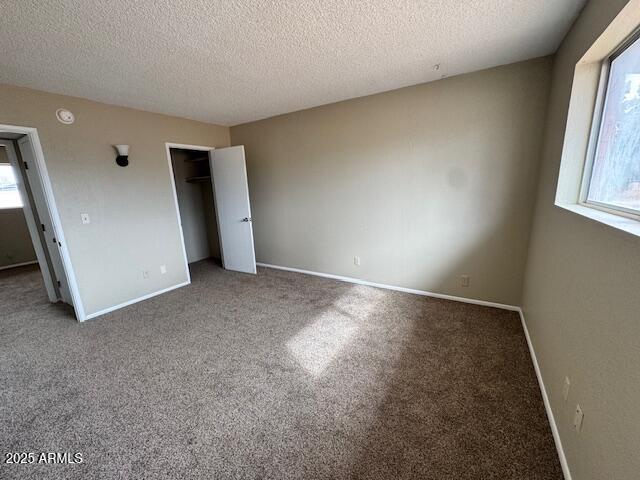 unfurnished bedroom featuring carpet flooring, a textured ceiling, and a closet