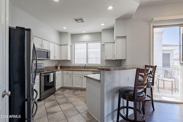 kitchen featuring kitchen peninsula, white cabinets, stainless steel appliances, and a wealth of natural light