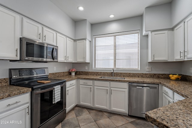 kitchen featuring appliances with stainless steel finishes, white cabinets, dark stone countertops, and sink