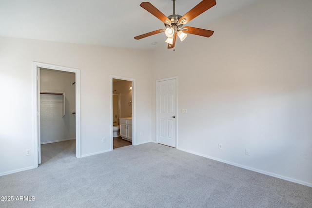 unfurnished bedroom with ceiling fan, vaulted ceiling, carpet flooring, a spacious closet, and connected bathroom