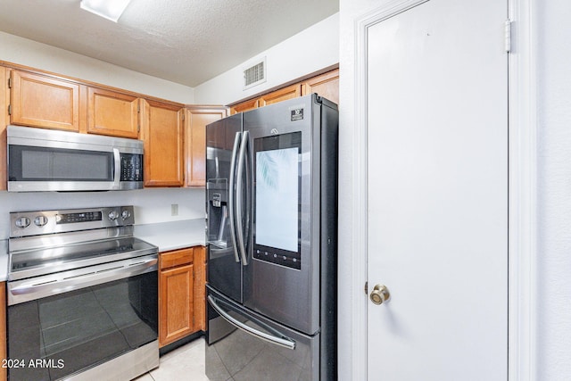 kitchen featuring light tile patterned floors, a textured ceiling, visible vents, light countertops, and appliances with stainless steel finishes