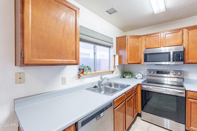 kitchen with light tile patterned floors, visible vents, stainless steel appliances, light countertops, and a sink