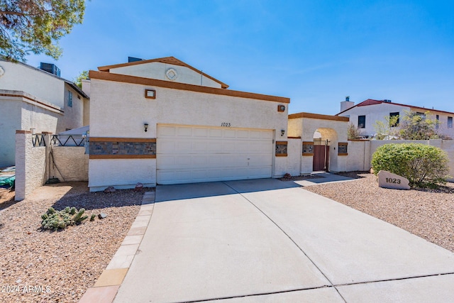 view of front of property featuring an attached garage, fence, concrete driveway, a gate, and stucco siding