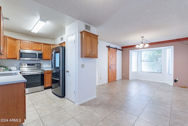 kitchen with stainless steel appliances, a barn door, light countertops, and visible vents