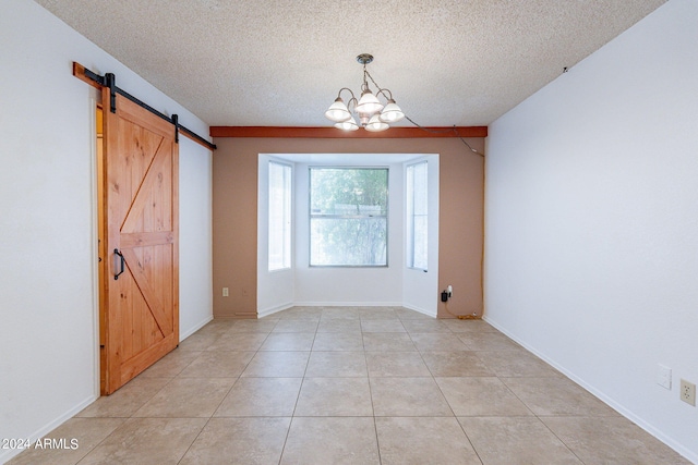 unfurnished room with light tile patterned floors, a barn door, a textured ceiling, a chandelier, and baseboards