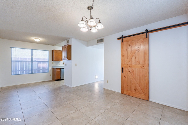 interior space with light tile patterned floors, a barn door, visible vents, and a textured ceiling